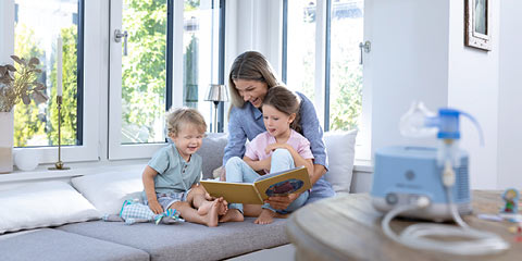 Eine Mutter liest ihren beiden Kindern aus einem Buch vor