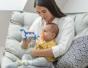Junge Mutter hilft Ihrem Baby beim inhalieren mit der VORTEX