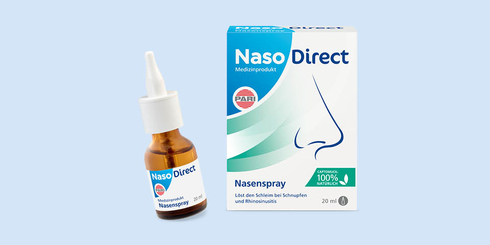 Produktabbildung: Vor einem blau-grauen Hintergrund steht eine Pumpspray-Flasche NasoDirect Nasenspray. Rechts daneben steht die dazugehörige Handels-Verpackung.