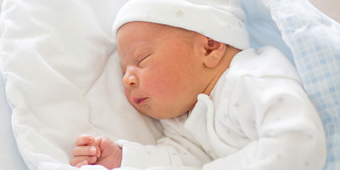 Un bébé dort tourné vers la gauche dans un lit pour bébé