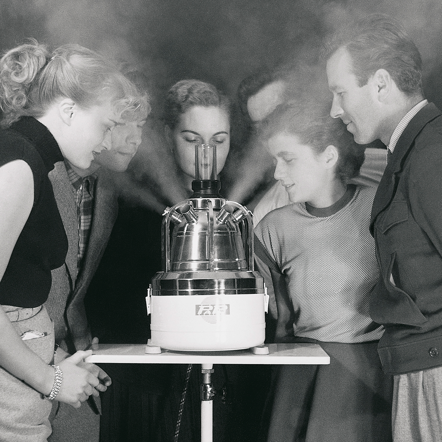Development of the PARI large-capacity nebulizer – a group of people stands around a table and looks at a device from which steam is emitted.