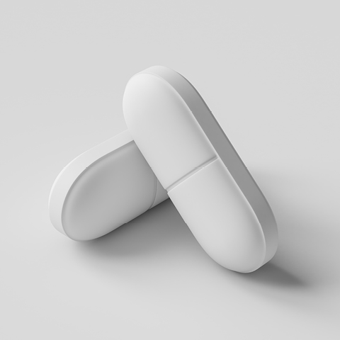 Two large, white capsule-shaped tablets lie on a smooth, light gray surface.