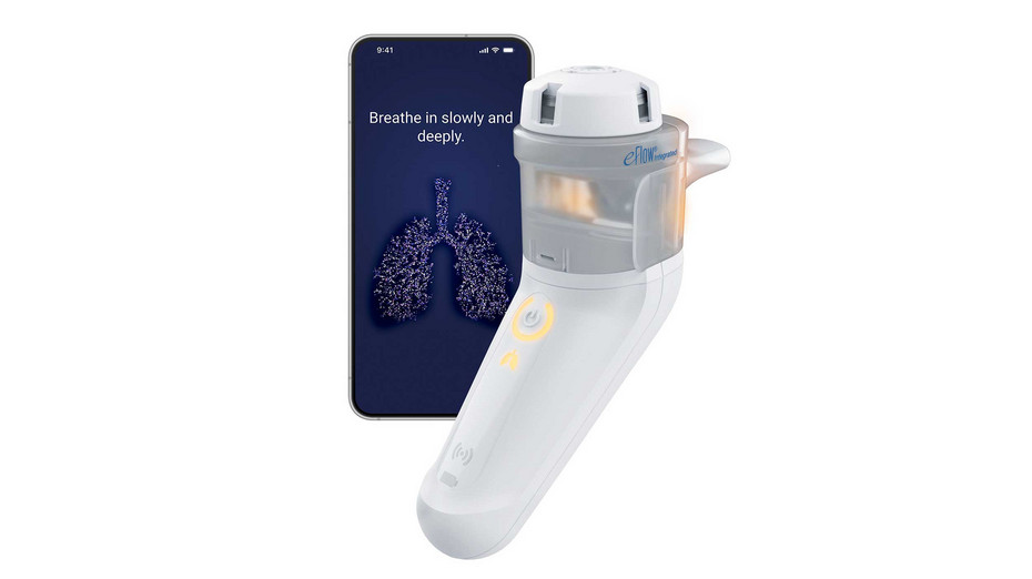 A white and gray PARI eFlow Integrated stands upright next to a smartphone displaying instructions to "Breathe in slowly and deeply" above a digital illustration of lungs.