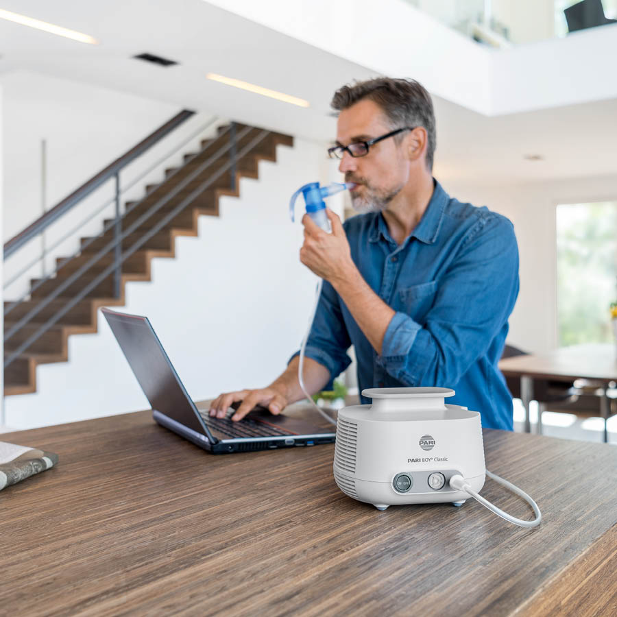 A pharmacist demonstrates a PARI COMPACT2 inhalation device on a counter in the pharmacy.