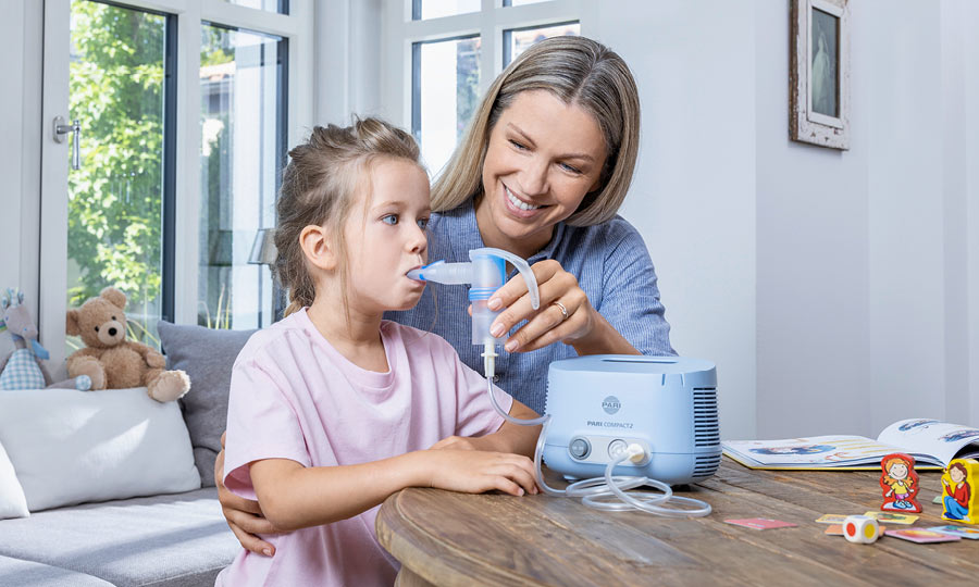 Mother helps her child during the inhalation therapy with a nebuliser.