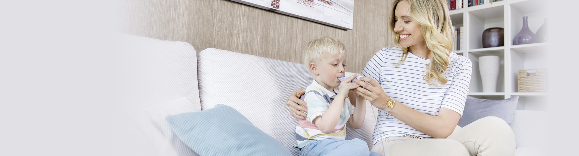 Mother helps her child during the inhalation therapy with a nebuliser.